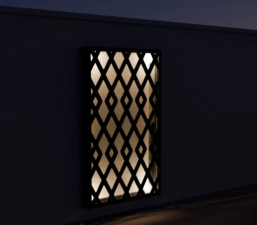 The Trelace Frame at night, lit by its own edge light: the wall behind the screen glows evenly and the lattice stands in silhouette.